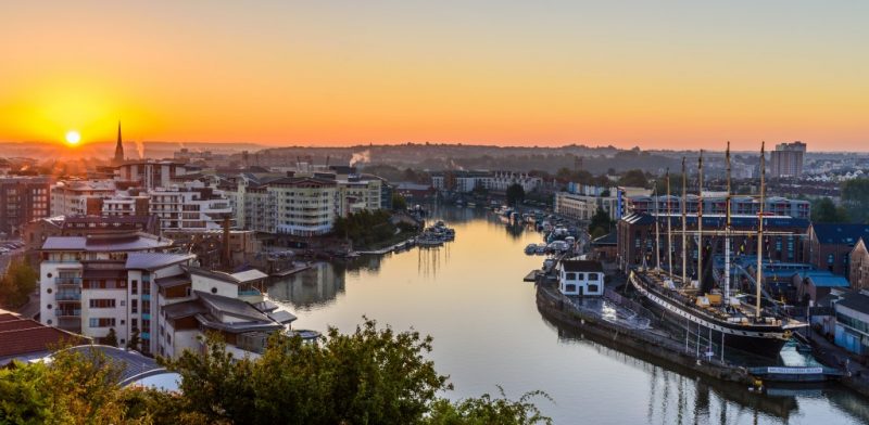 Aerial view of the river in Bristol at sunset, with orange sky above the city skyline