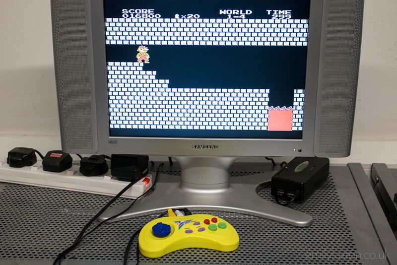 Old silver Samsung TV with a yellow games controller in front and a dated black and white video game on the screen