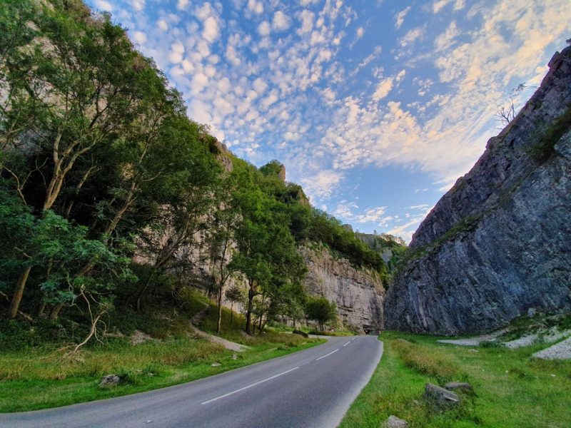 Empty road in Cheddar Gorge with steep grey rock cliffs on either side