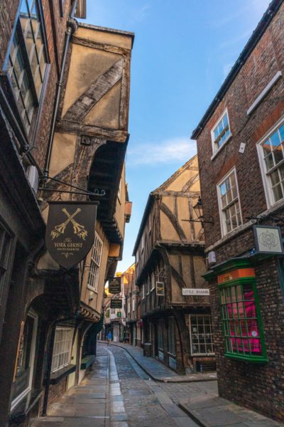 narrow cobbled street in York lined with medieval buildings all different shapes and sizes 