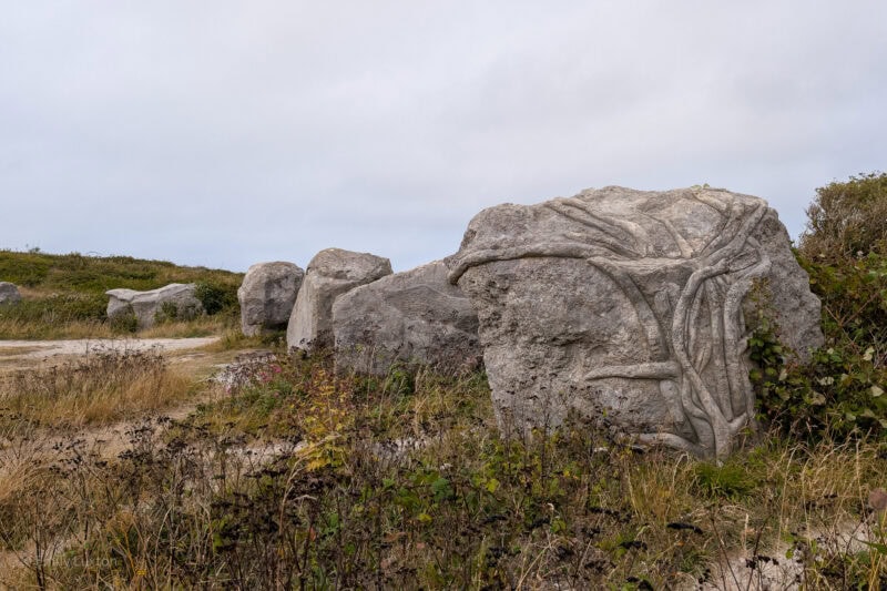 Large grey rock with a swirled design carved into it at Tout Quarry Sculpture Park